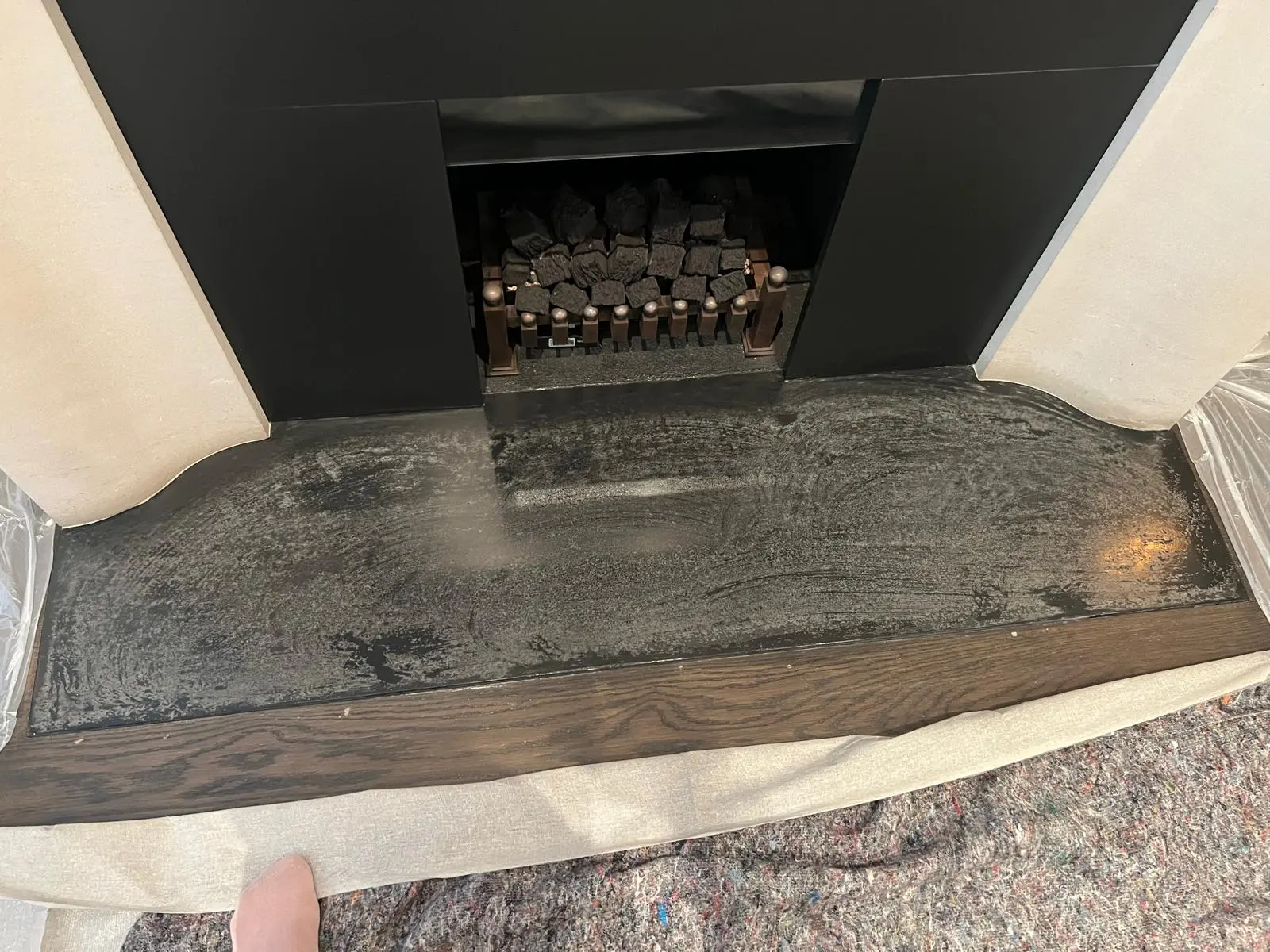Stone fireplace and hearth before restoration, soot-stained surface and dulled finish, London period property