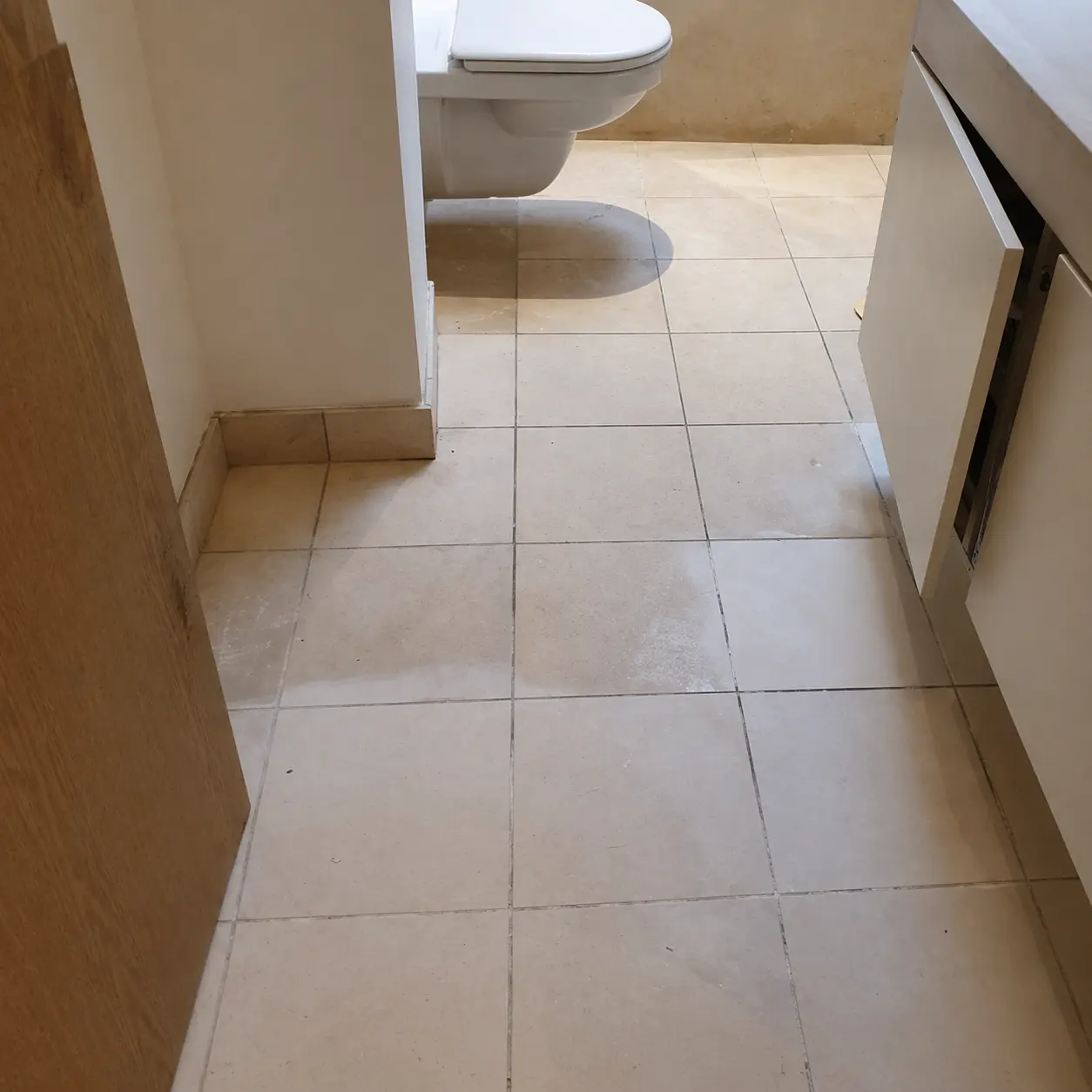 Dulled and stained limestone bathroom floor before restoration