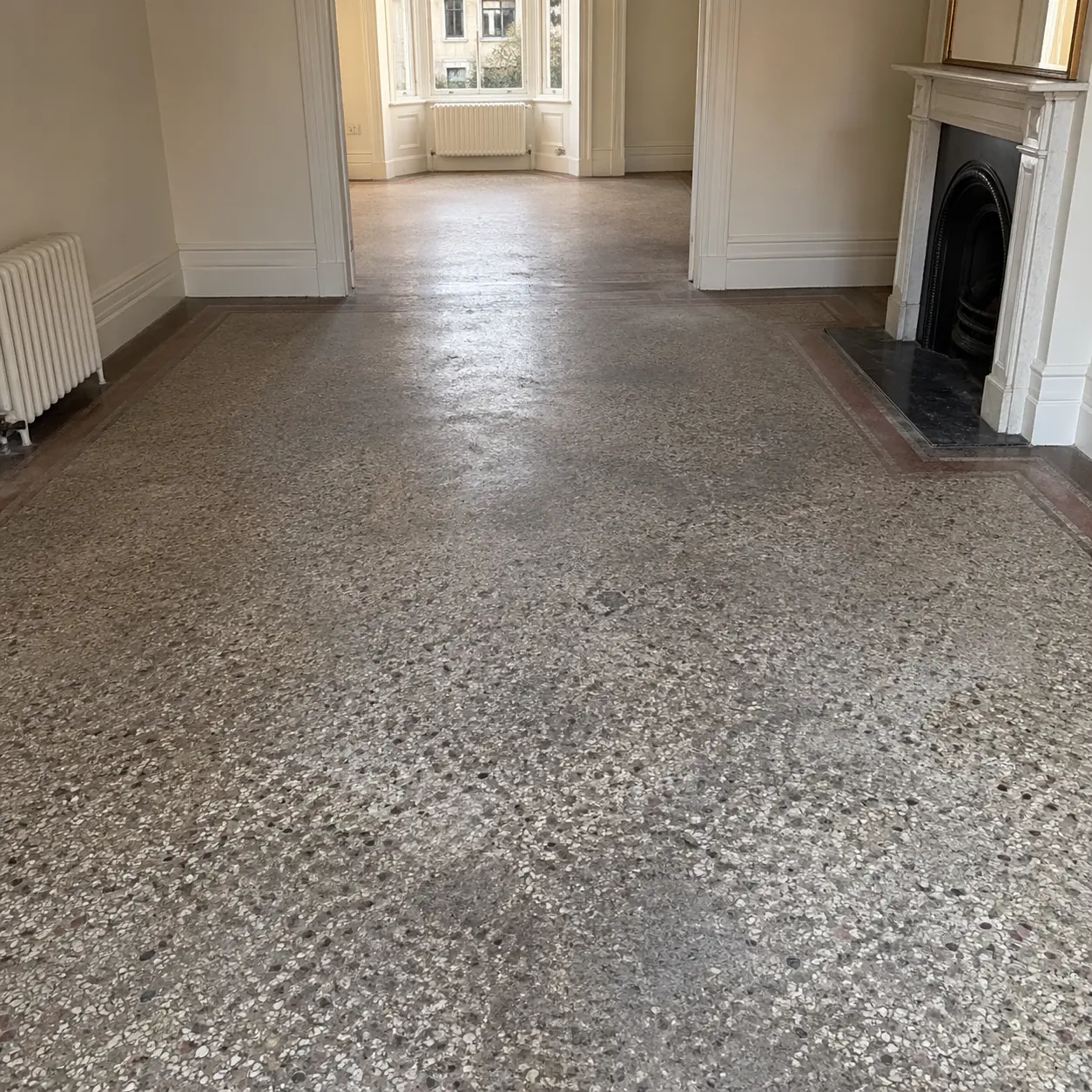 Period terrazzo fireplace and hearth with surface wear and lippage before restoration
