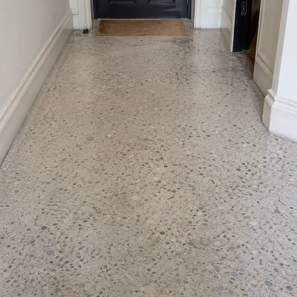 Period Italian terrazzo hallway with worn aggregate and lippage before restoration