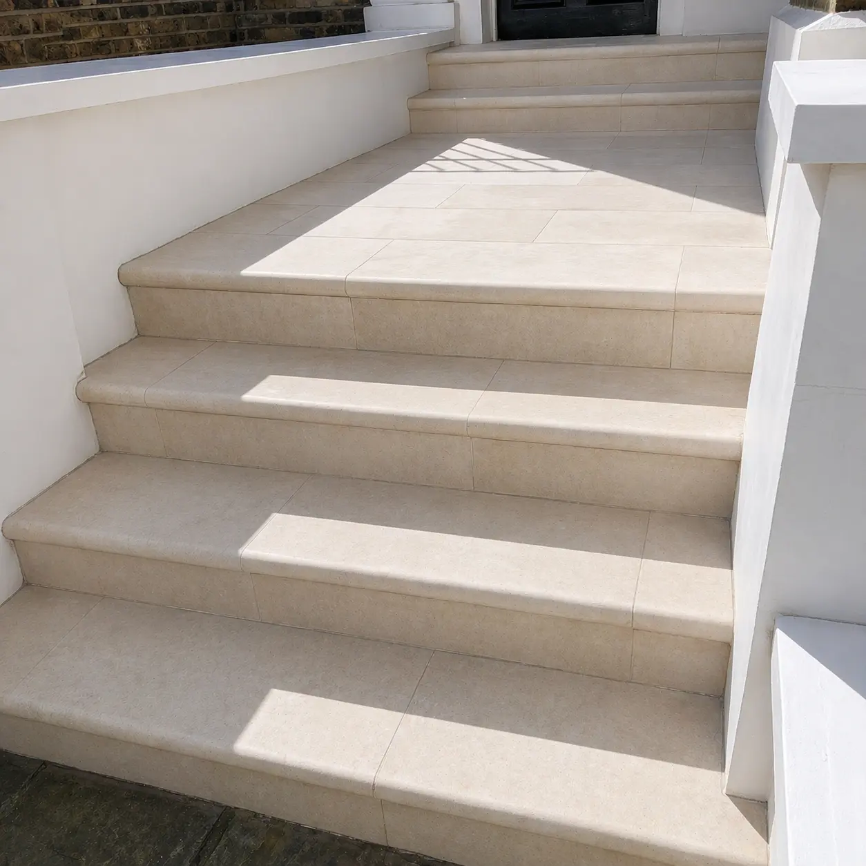 Travertine entrance stairs after restoration, uniform honed finish with warm natural colour restored