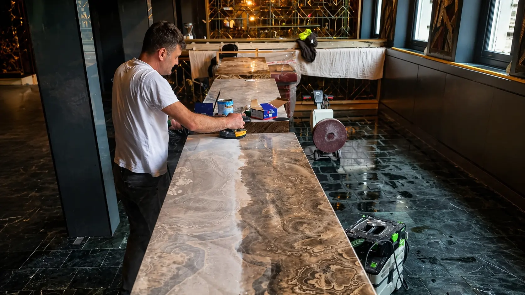Marius on site restoring an onyx bar top in a London hospitality venue, hand-polishing the surface with a rotary sander